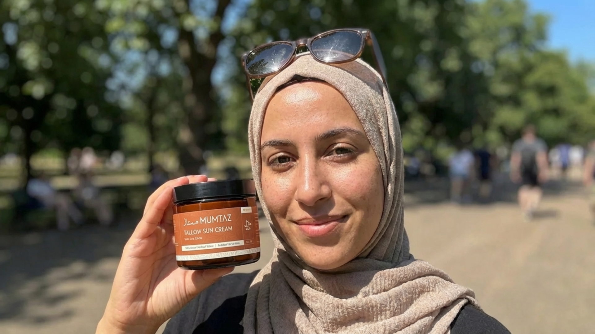 A Muslim woman holding a jar of Mumtaz Tallow Sun Cream outdoors